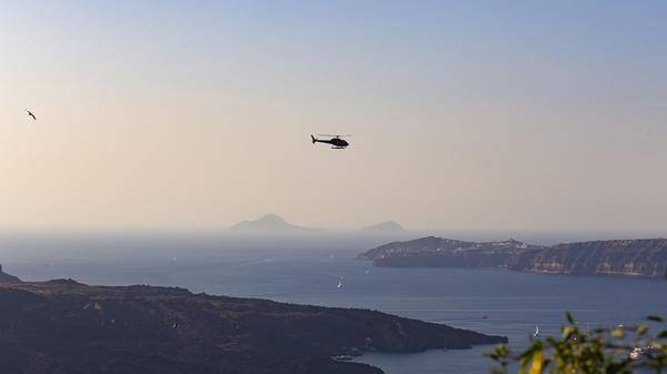 Helicopter flying over sunny seaside location