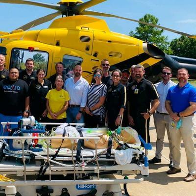 Large group of PHI and MCH staff in front of air ambulance helicopter