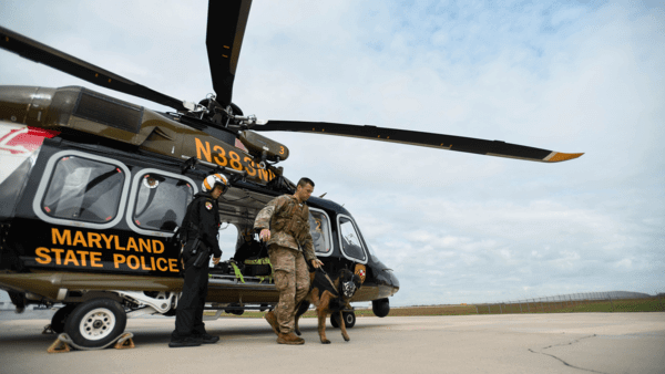 Military man with dog by helicopter