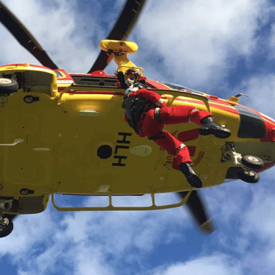 Air rescue worker being lowered out of helicopter