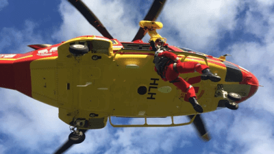 Air rescue worker being lowered out of helicopter