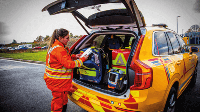 Worker putting medical kit bag in boot of car